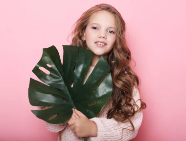 Güzellik ve moda konsepti: Pembe elbiseli ve elinde çiçekle küçük bir kız