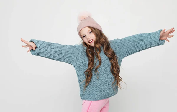 童年、时尚和人的概念：戴着粉色帽子、穿着蓝色毛衣的小女孩在白色背景上跳跃. — 图库照片