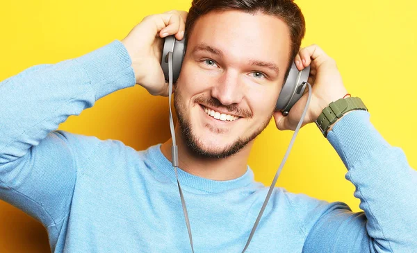 Estilo de vida y el concepto de la gente: Feliz joven escuchando música con auriculares sobre fondo amarillo —  Fotos de Stock
