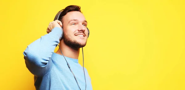 Jóképű ember licencelés a zene felett sárga háttér — Stock Fotó