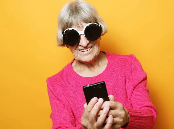 Yaşlı büyükannesi torunlarıyla telefonda konuşuyor, gülümsüyor ve onları selamlıyor..