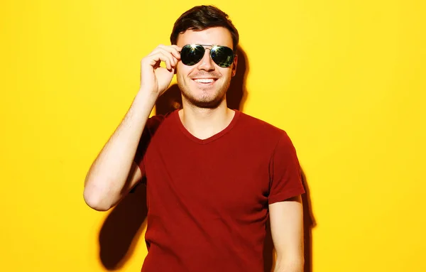 Detailní portrét mladého muže příležitostné nosí sluneční brýle na žlutém podkladu — Stock fotografie