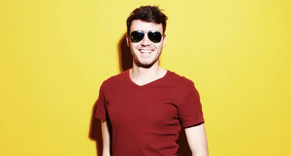 Portrait of a young man wearing sunglasses on yellow background — Stock Photo, Image