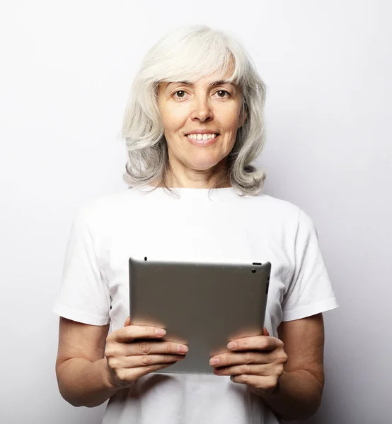 Старшая счастливая женщина, используя ipad изолированы на белом фоне — стоковое фото