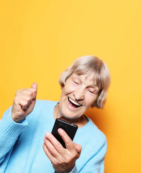 Mulher velha vestindo camisola azul falando no telefone celular — Fotografia de Stock