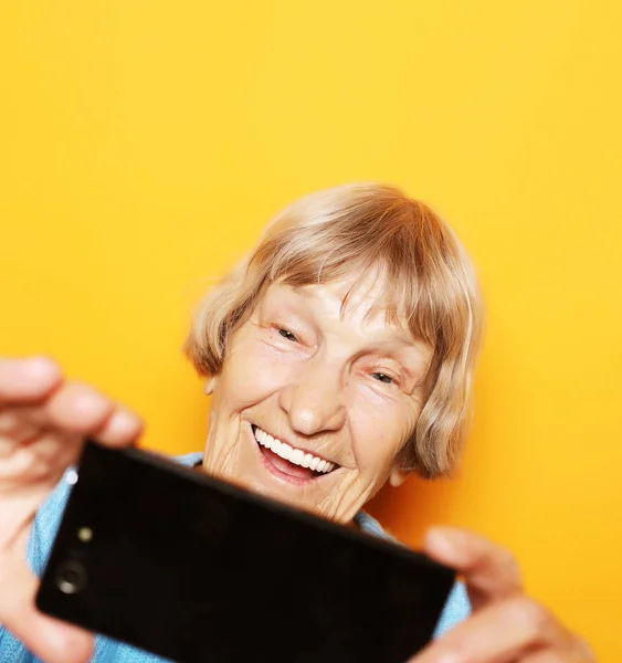 Estilo de vida, tehnologia e conceito de pessoas: vovó em suéter azul sorri e tira uma selfie — Fotografia de Stock