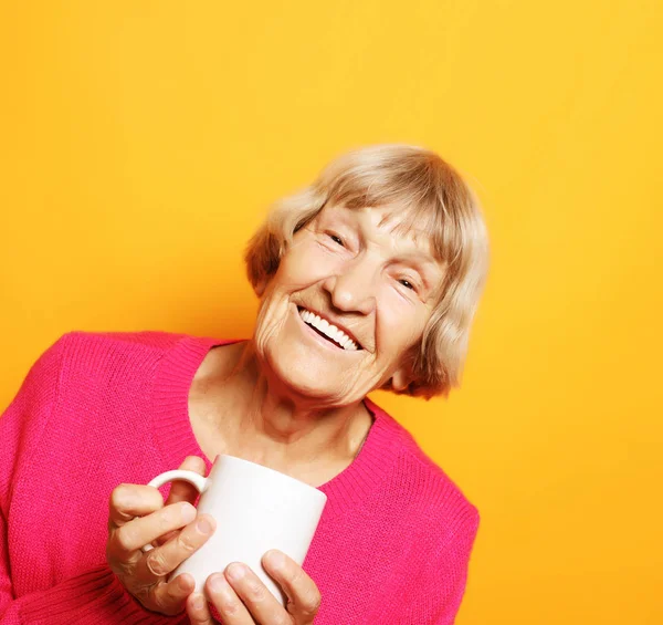 Portret staruszki uśmiechniętej, trzymającej filiżankę kawy, herbatę — Zdjęcie stockowe