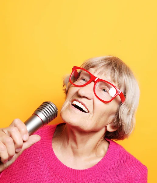 Koncepcja życia i ludzi: portret śmieszne babci różowym swetrze trzyma mikrofon — Zdjęcie stockowe
