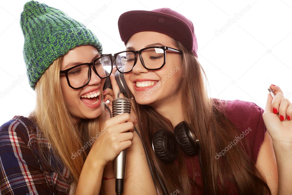 lifestyle, happiness, emotional and people concept: two beauty girls with a microphone singing and having fun