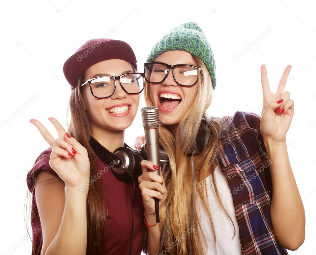 lifestyle, happiness, emotional and people concept: two beauty girls with a microphone singing and having fun