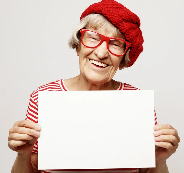 Mulher sênior feliz com placa de publicidade em branco ou espaço de cópia, sobre fundo cinza claro, close-up — Fotografia de Stock