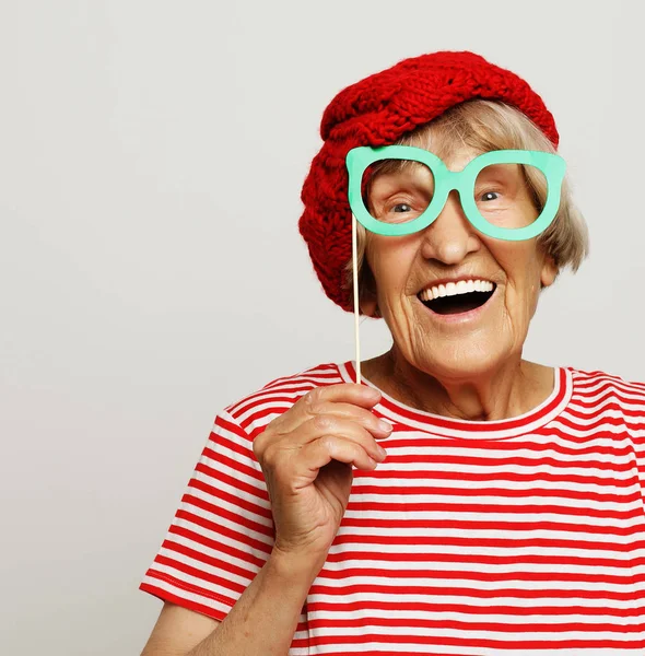 Lifestyle, emotion and people concept: funny grandmother with fake glasses, laughs and ready for party — Stock Photo, Image