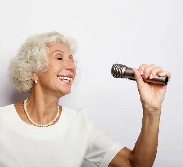 Estilo de vida y el concepto de la gente: Retrato de la encantadora abuela moderna sostiene el soporte del micrófono y canta — Foto de Stock