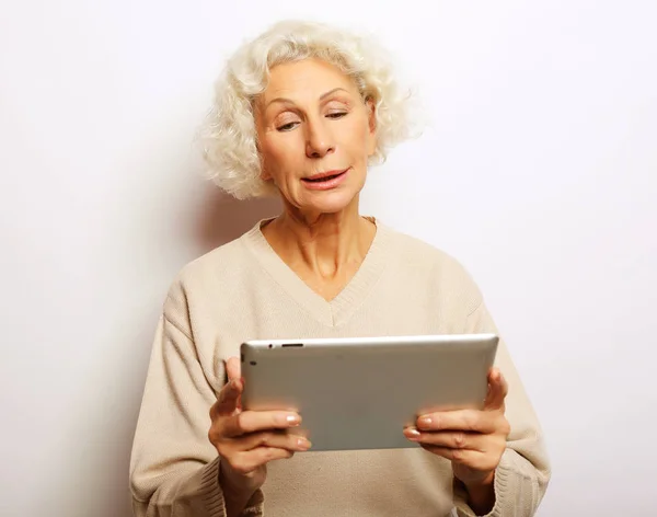 Mulher madura feliz usando um tablet, se comunica com filhos e netos — Fotografia de Stock