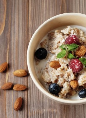 sağlıklı beslenme ve diyet kavramı: yulaf lapası kase tepesinde taze yaban mersini ve ahududu ahşap tablo