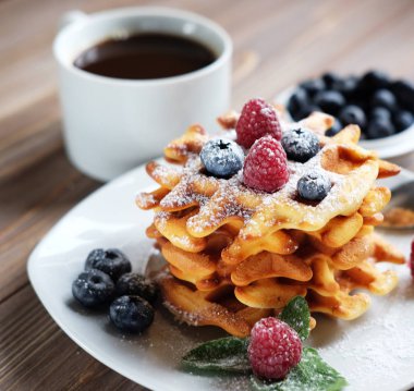 Waffle beyaz plaka ve kahve, çilek ile yakın çekim.