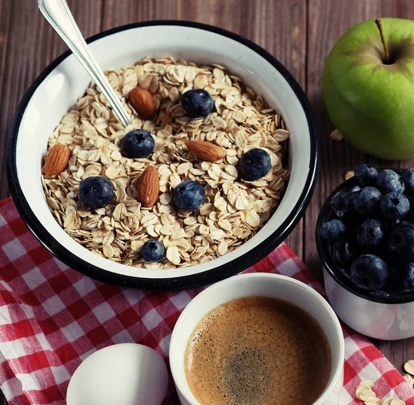 Ein gesundes Frühstück ist ein guter Start in einen neuen Tag. Haferbrei, Kaffee, Apfel, Beeren und Nüsse auf einem Holztisch. — Stockfoto