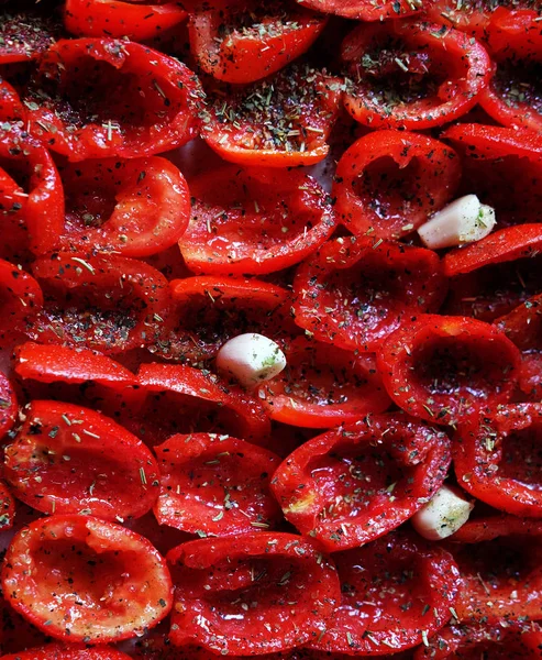 西红柿躺在烘烤板上, 准备烘烤。晒干的西红柿和大蒜。食物背景。特写 — 图库照片
