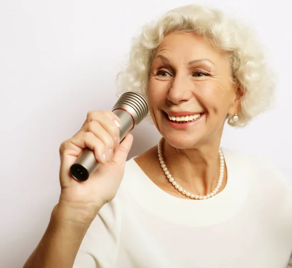 Образ жизни и концепция людей: портрет очаровательной современной бабушки держит микрофон — стоковое фото