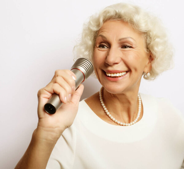 lifestyle and people concept: Portrait of charming modern grandmother holds up the microphone