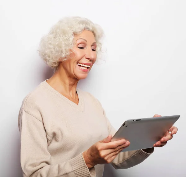 Lycklig mogen kvinna som använder en tablett, kommunicerar med barn och barnbarn — Stockfoto