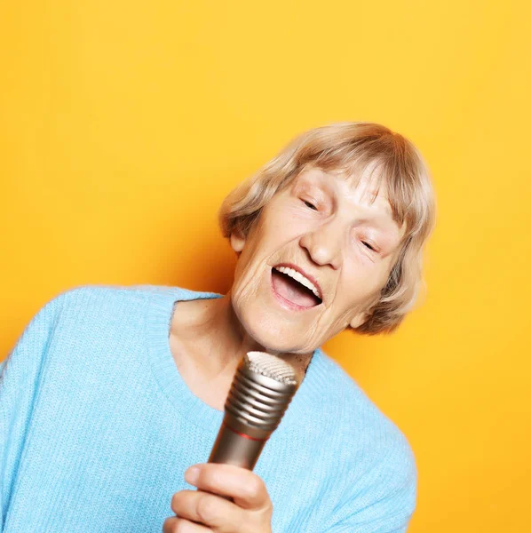 Τρόπο ζωής και άνθρωποι έννοια: ευτυχής ανώτερος ηλικιωμένη γυναίκα που τραγουδά με το μικρόφωνο — Φωτογραφία Αρχείου