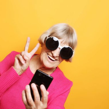 Bir akıllı telefon tutarak ve v-sign yapma yaşlı Bayan