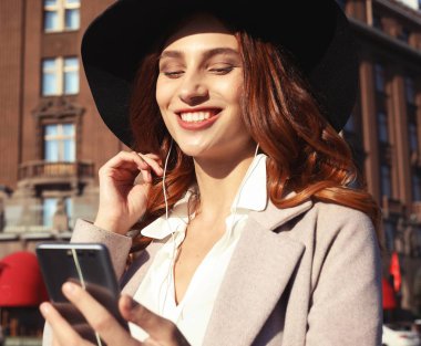 Bir sonbahar günü şehirde yürüyen mutlu bir kadın.
