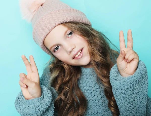 Felice concetto di persone - sorridente bambina mostrando gesto di pace con le dita su sfondo blu — Foto Stock