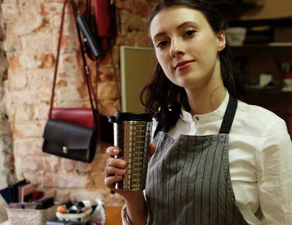 young master woman drinks coffee in a workshop, lunch break