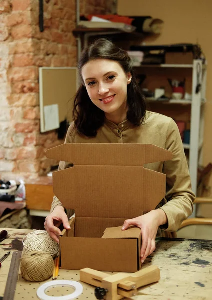 Giovane donna bruna piega scatola di imballaggio nel laboratorio di cucito — Foto Stock
