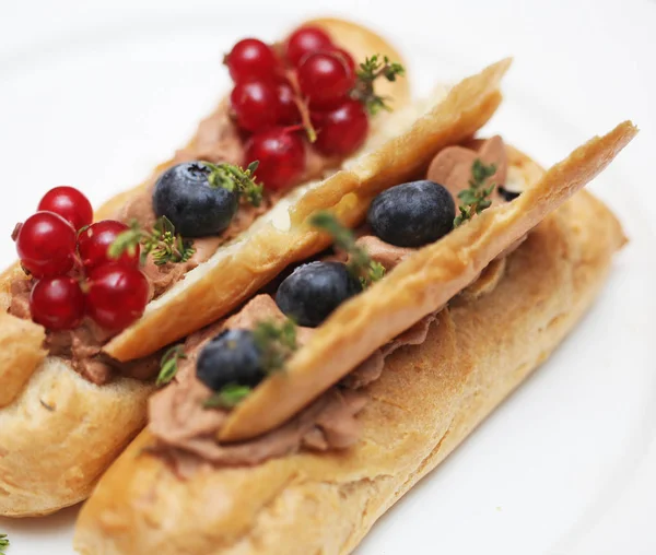 Eclairs mit frischen Beeren auf weißem Teller, handgemacht, kulinarisches Thema, Nahaufnahme — Stockfoto