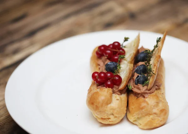 Eclairs mit frischen Beeren auf weißem Teller, handgemacht, kulinarisches Thema, Nahaufnahme — Stockfoto