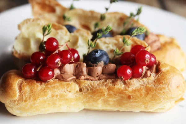 Eclairs mit frischen Beeren auf weißem Teller, handgemacht, kulinarisches Thema, Nahaufnahme — Stockfoto