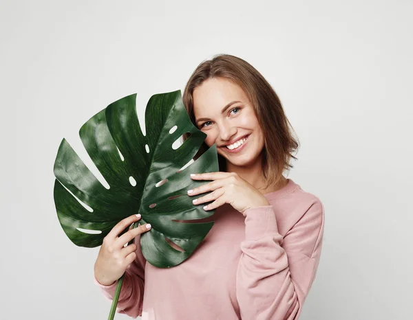 ライフスタイルと人々のコンセプト - 大きな熱帯の花の葉を持ち、笑顔の美しい若い女性 — ストック写真