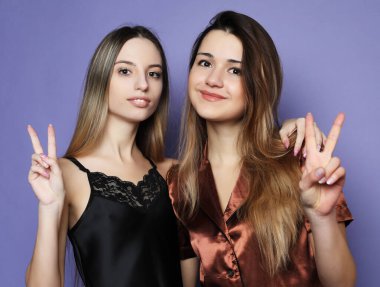 Yaşam tarzı ve insan konsepti: pijama giymiş iki güzel kız kucaklaşıp selfie çekiyor.