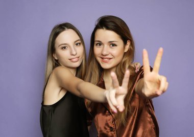 Yaşam tarzı ve insan konsepti: pijama giymiş iki güzel kız kucaklaşıp selfie çekiyor.