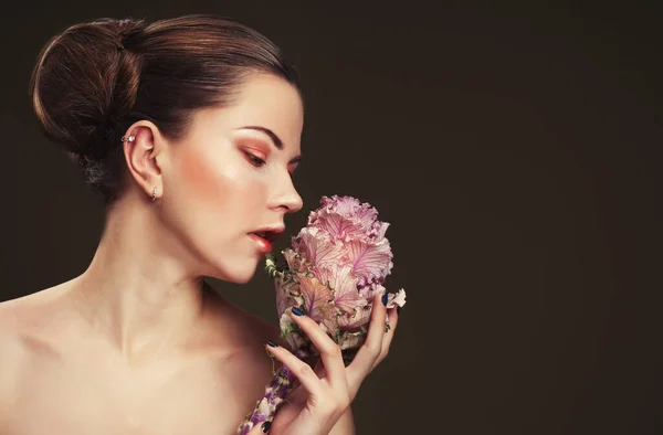 Vacker ung kvinna med makeup i mjuka färger håller en stor rosa blomma, skönhet koncept — Stockfoto