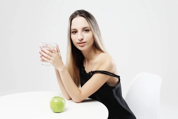 Estilo de vida, salud y concepto de personas - mujer joven con pijama sosteniendo un vaso de agua — Foto de Stock