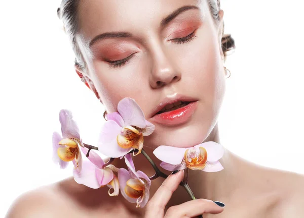 Krásná mladá žena s jasným make-up v růžových tónech drží orchidej, natáčení na bílém pozadí — Stock fotografie