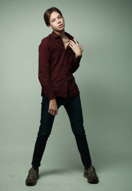 Çekici genç çocuk gri arka plan üzerinde stüdyoda poz