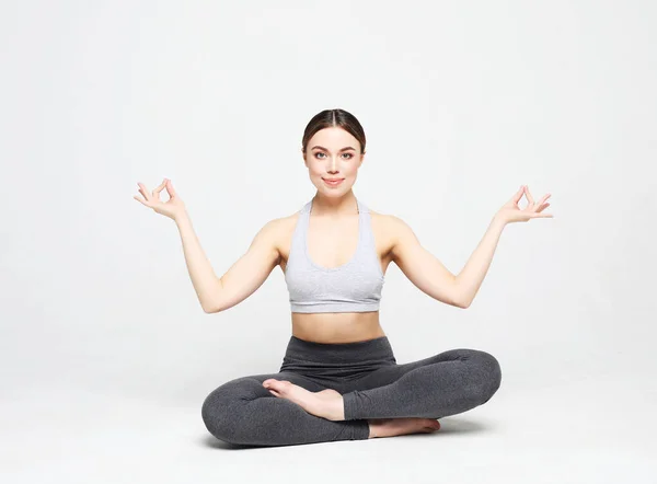 Młoda kobieta ćwiczy jogę, ćwiczy, nosi odzież sportową, kręci studio na białym tle — Zdjęcie stockowe