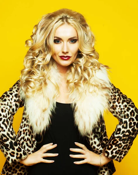 Belle femme sensuelle aux cheveux blonds luxueux en lingerie et manteau de fourrure posant sur fond jaune — Photo