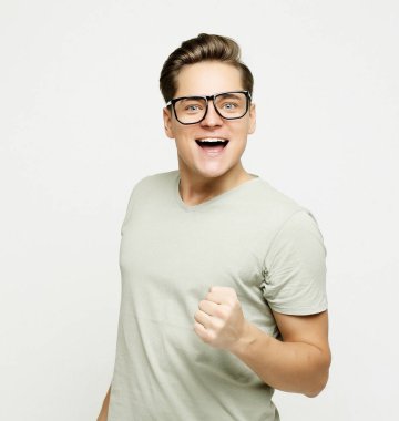 Mutlu genç yakışıklı adam el kol hareketi yapıyor ve ağzını kapalı tutuyor.