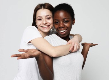 Mutlu ırklar arası homoseksüel çift kucaklaşması. Afro-Amerikalı kız ve onun büyüleyici beyaz kız arkadaşı..