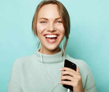 Kulaklıklı güzel genç bir kadın müzik dinliyor.