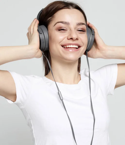 Vacker ung kvinna lyssnar på musik i hörlurar — Stockfoto