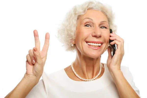Estilo de vida, tehnología y el concepto de la gente: señora mayor sosteniendo un teléfono inteligente haciendo v-signo — Foto de Stock