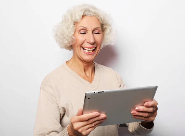 Lycklig mogen kvinna som använder en tablett, kommunicerar med barn och barnbarn — Stockfoto