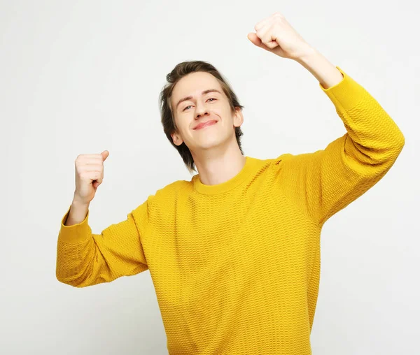 Mladý muž slaví vítězství nad bílým pozadím — Stock fotografie